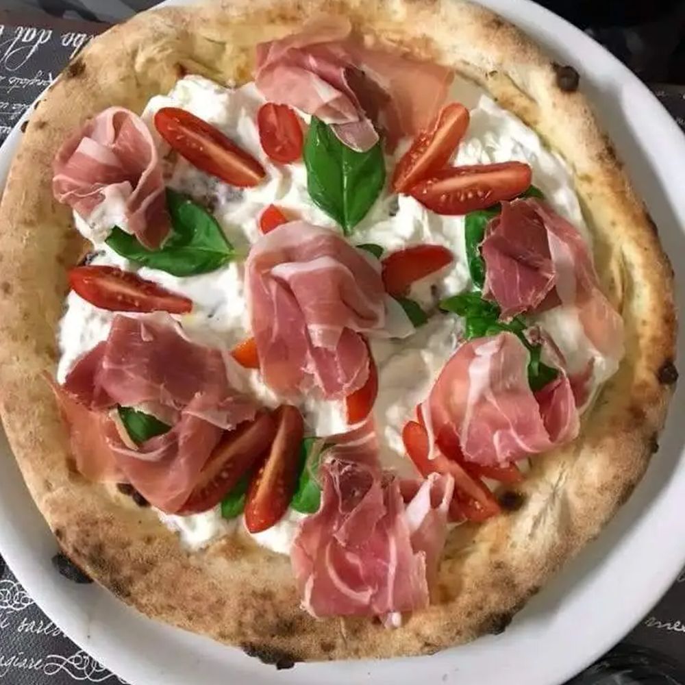 Pizza con crudo e stracciatella fotografata sul tavolo